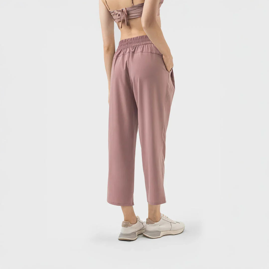 Vista posterior de pantalón deportivo rosa terracota con pretina elástica y corte relajado sobre el tobillo.