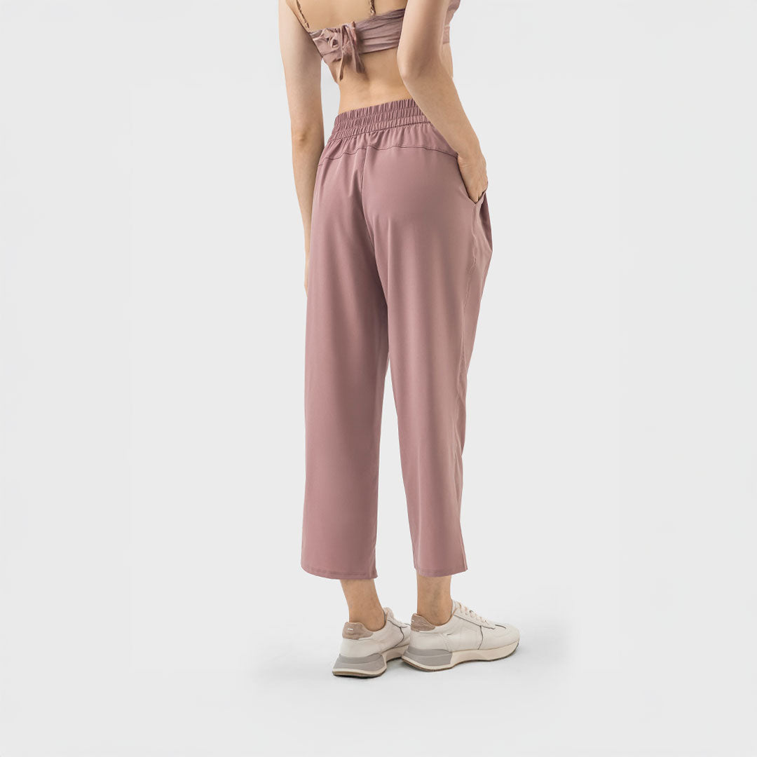 Vista posterior de pantalón deportivo rosa terracota con pretina elástica y corte relajado sobre el tobillo.