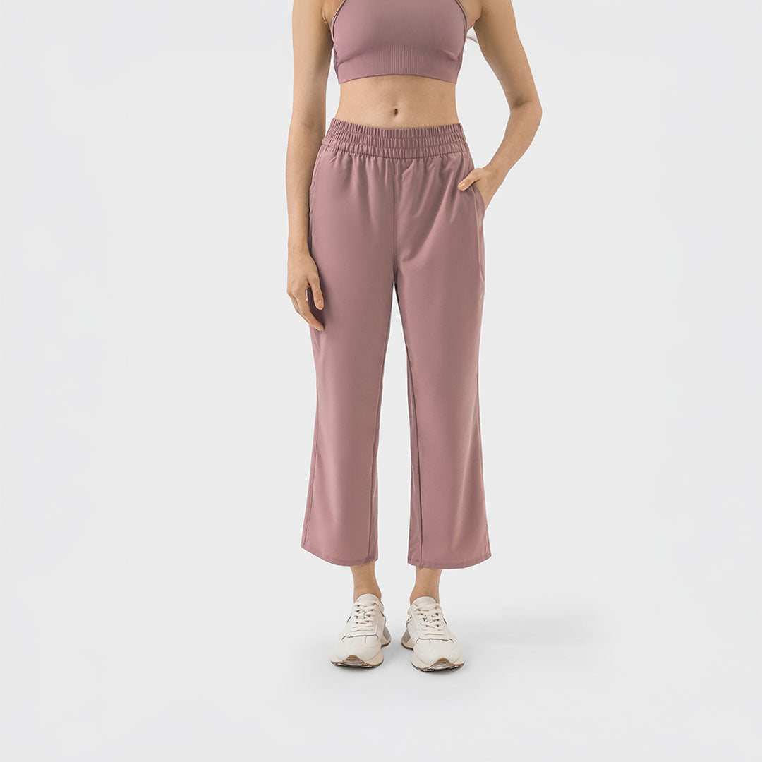 Mujer usando pantalón deportivo rosa terracota estilo cropped con cintura elástica y bolsillos, ideal para yoga o uso casual.